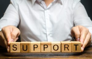 A man's hands arranging wooden blocks to spell out the word SUPPORT