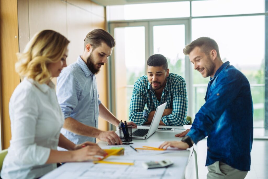 three men and one woman working together around a table