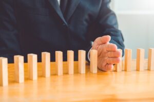 a man's hand stopping a series of dominoes