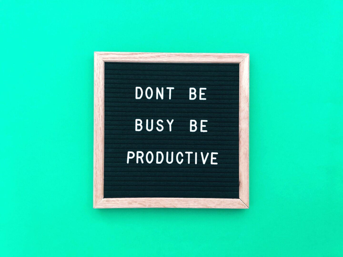 letters on a blackboard spelling out don't be busy be productive