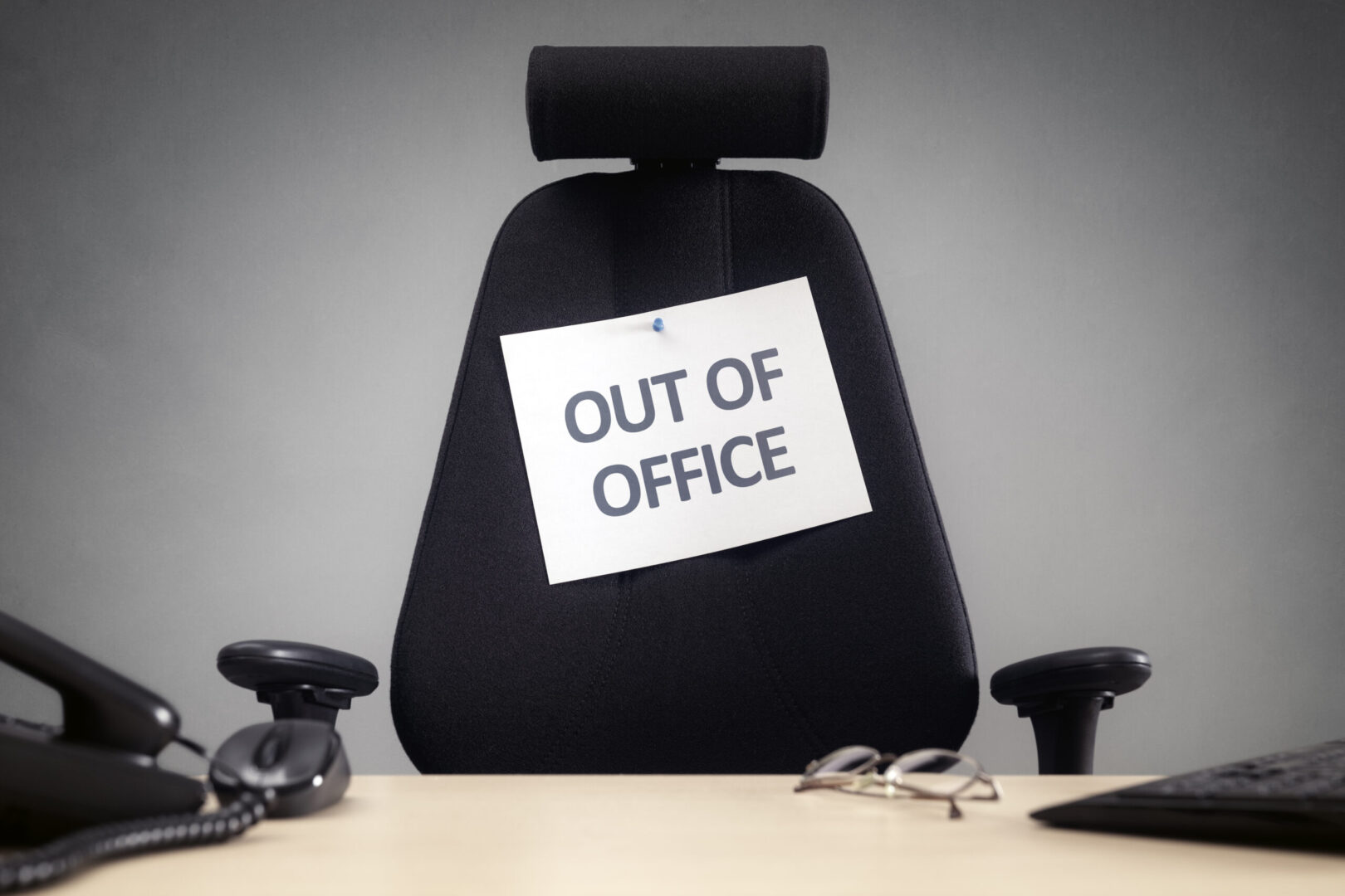black office chair with OUT OF OFFICE sign on it
